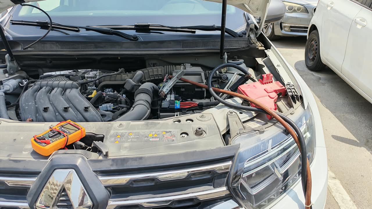 Technician performing a car battery jump start in Dubai